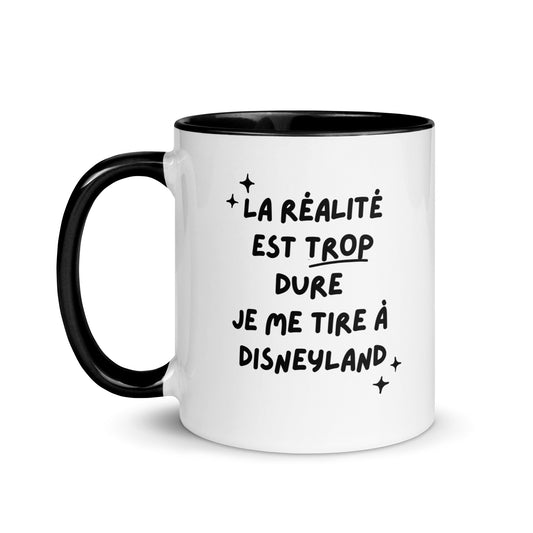 Tasse blanche brillante avec poignée, intérieur et rebord coloré noir avec inscription "La réalité est trop dure, je me tire à Disneyland"