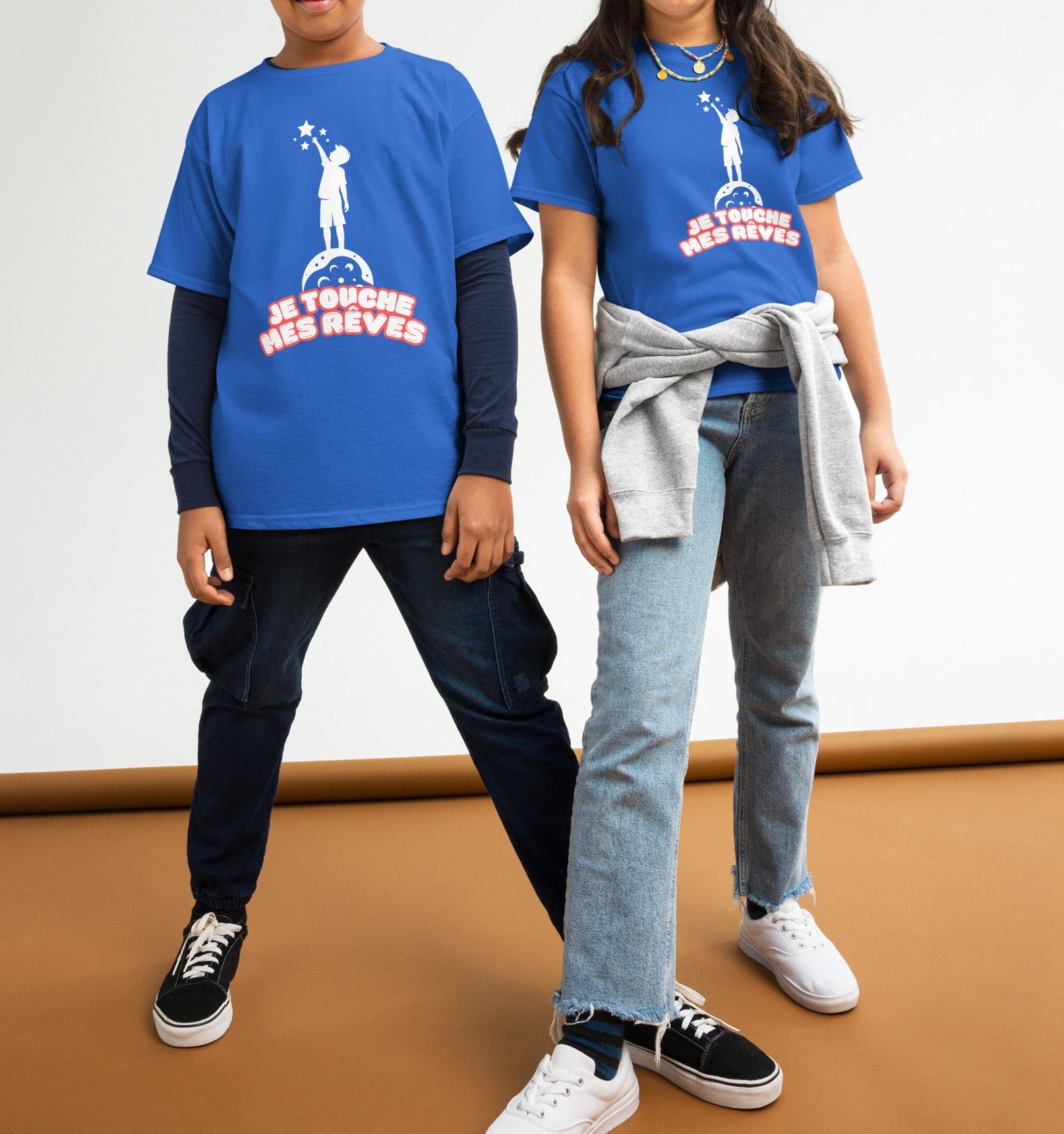 t-shirt de couleur bleu roi encolure ronde manche courte dessin enfant qui touche du bout des doigts les étoiles avec inscription : "je touche mes rêves" porté par un et une mannequin de 10 ans